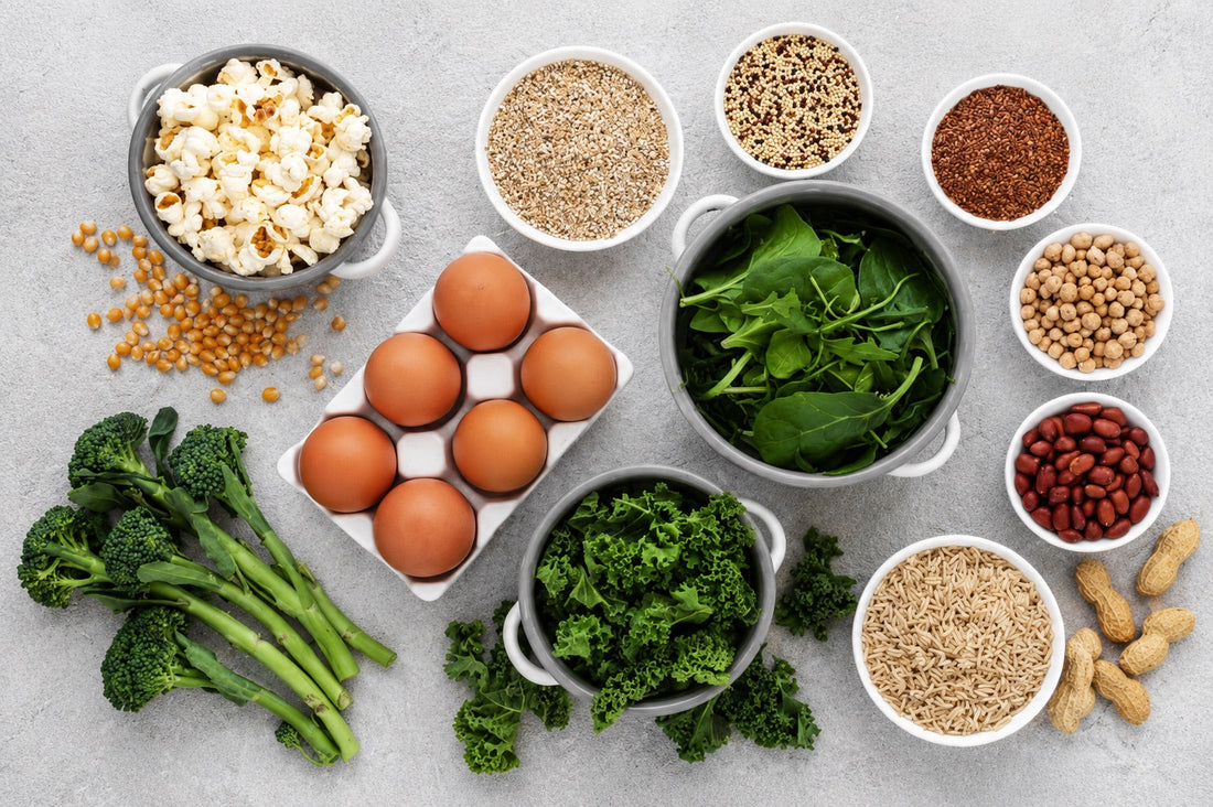 Flat lay of folate and B12 rich foods including spinach, kale, broccoli, eggs, legumes, seeds and whole grains